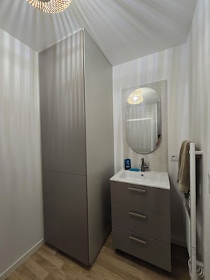 Ein Badezimmer im modernen Stil, mit einem großen Spiegel, einem Waschbecken und einem Handtuchhalter.
