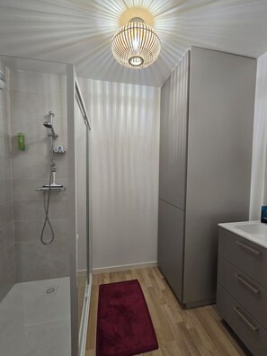 Ein modernes Badezimmer mit Dusche, Waschtisch und einer außergewöhnlichen Deckenleuchte.