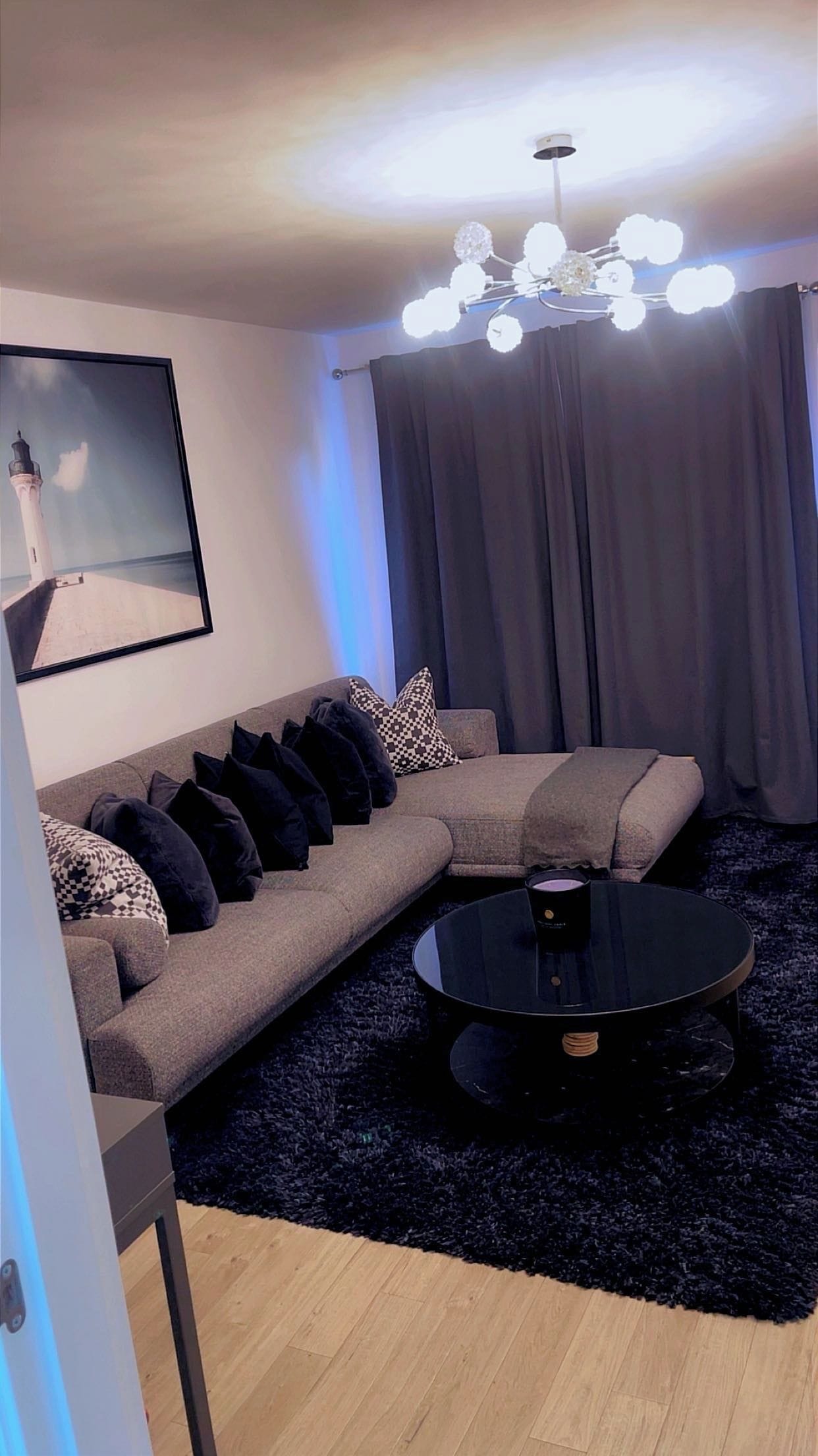 A modern living room with a sectional sofa, a round coffee table, and a chandelier.