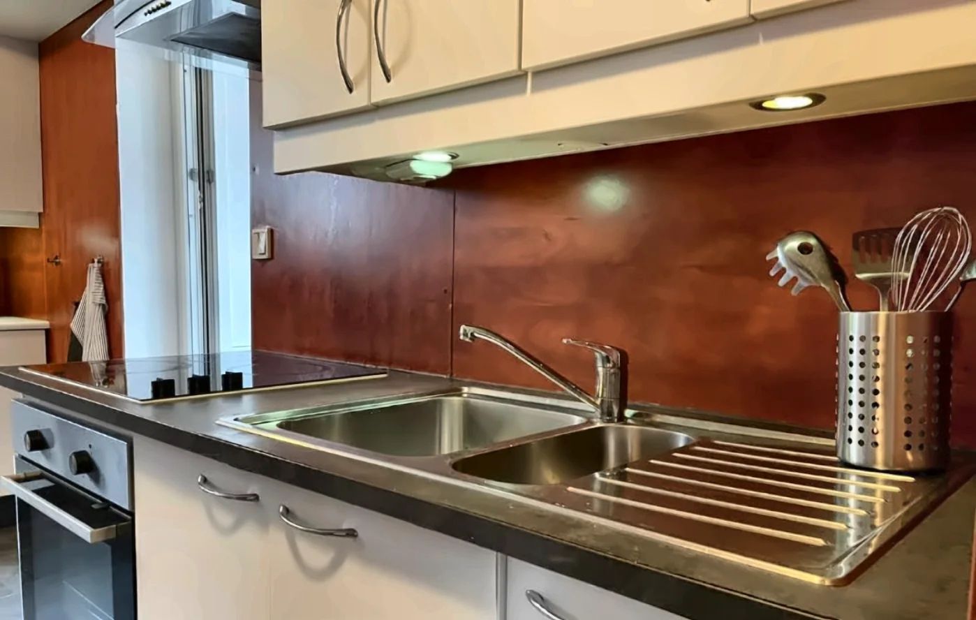A kitchen with stainless steel appliances, a double sink, and a utensil holder.