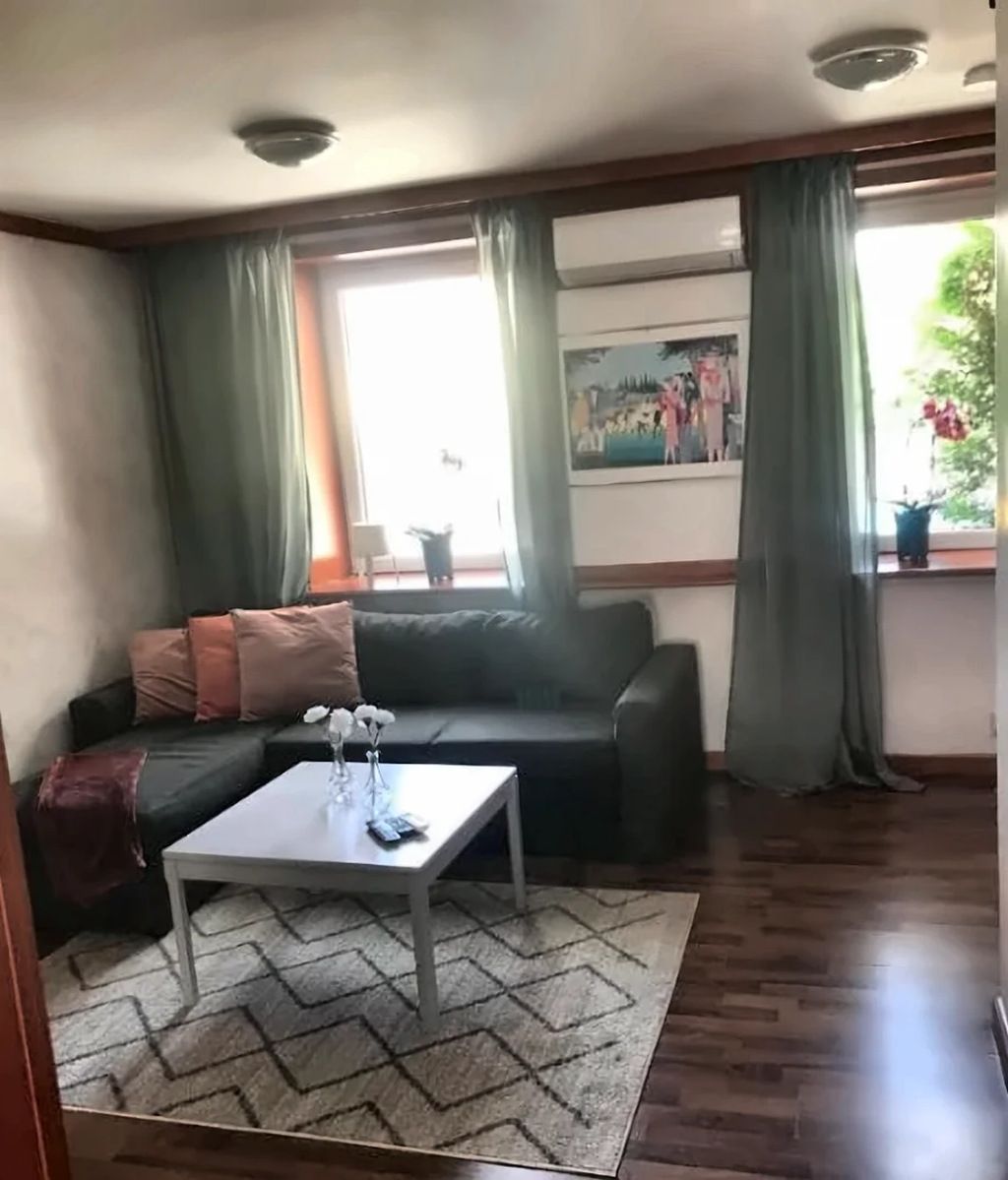 A living room with a sofa, a coffee table, and a window with curtains.