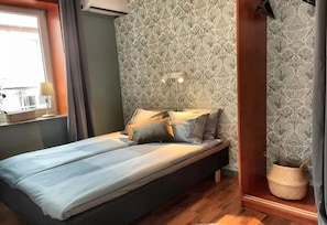 A single bed with a headboard, a bedside lamp, and a patterned wallpaper. - Astoria Apart Hotel (Skåne län)
