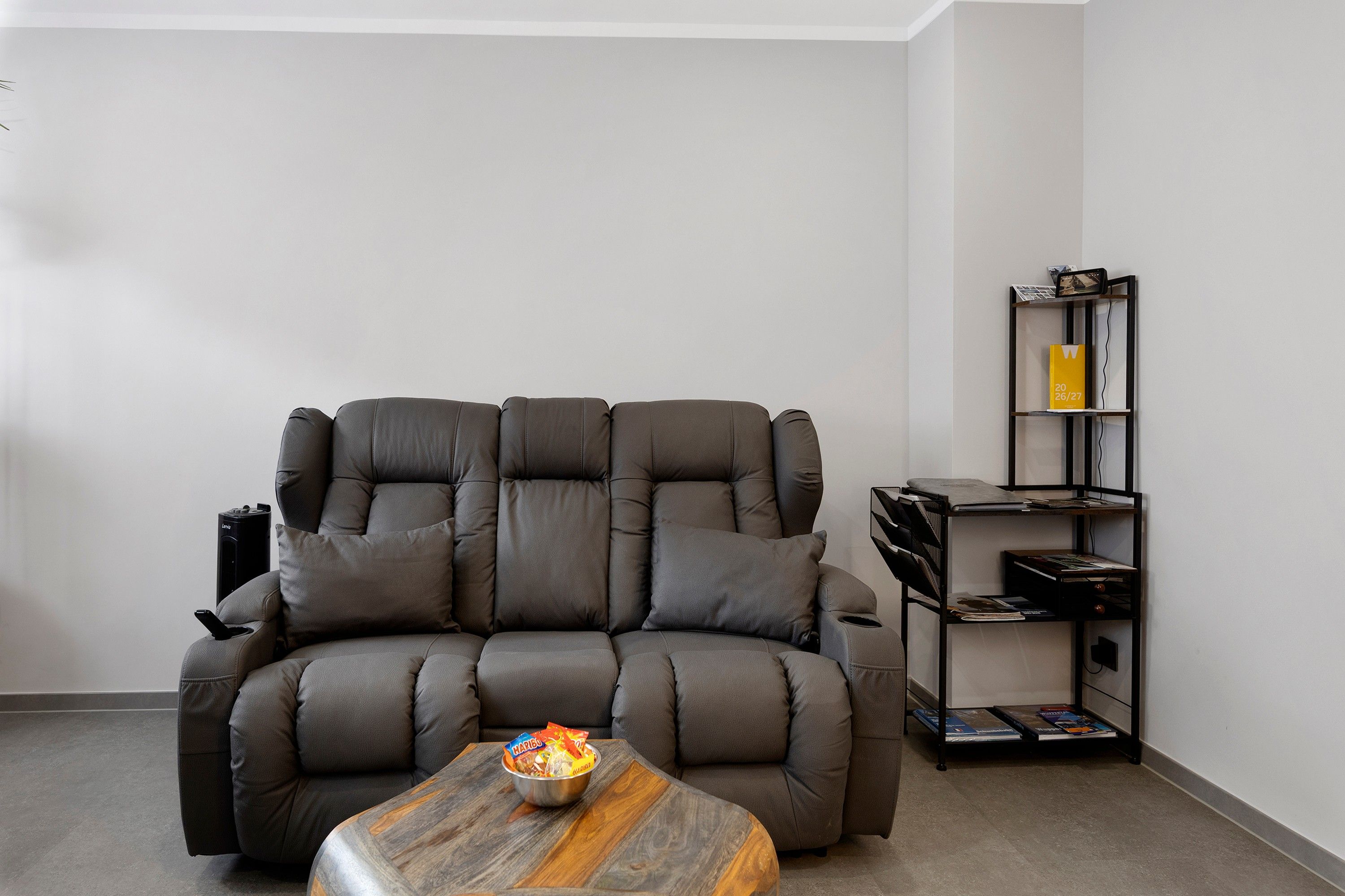 Ein modernes Wohnzimmer mit einer Eckcouch, einem Couchtisch und einem Bücherregal.