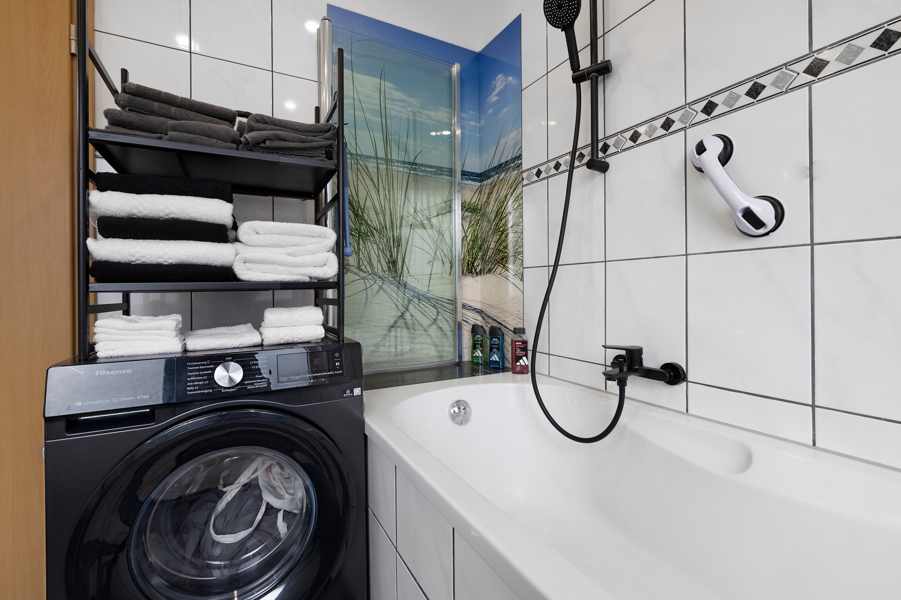 Ein modernes Badezimmer mit Waschmaschine, Badewanne und Dusche.