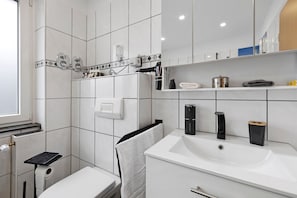 Ein modernes Badezimmer mit einem weißen Waschbecken, einem Handtuchhalter und einer Toilette.