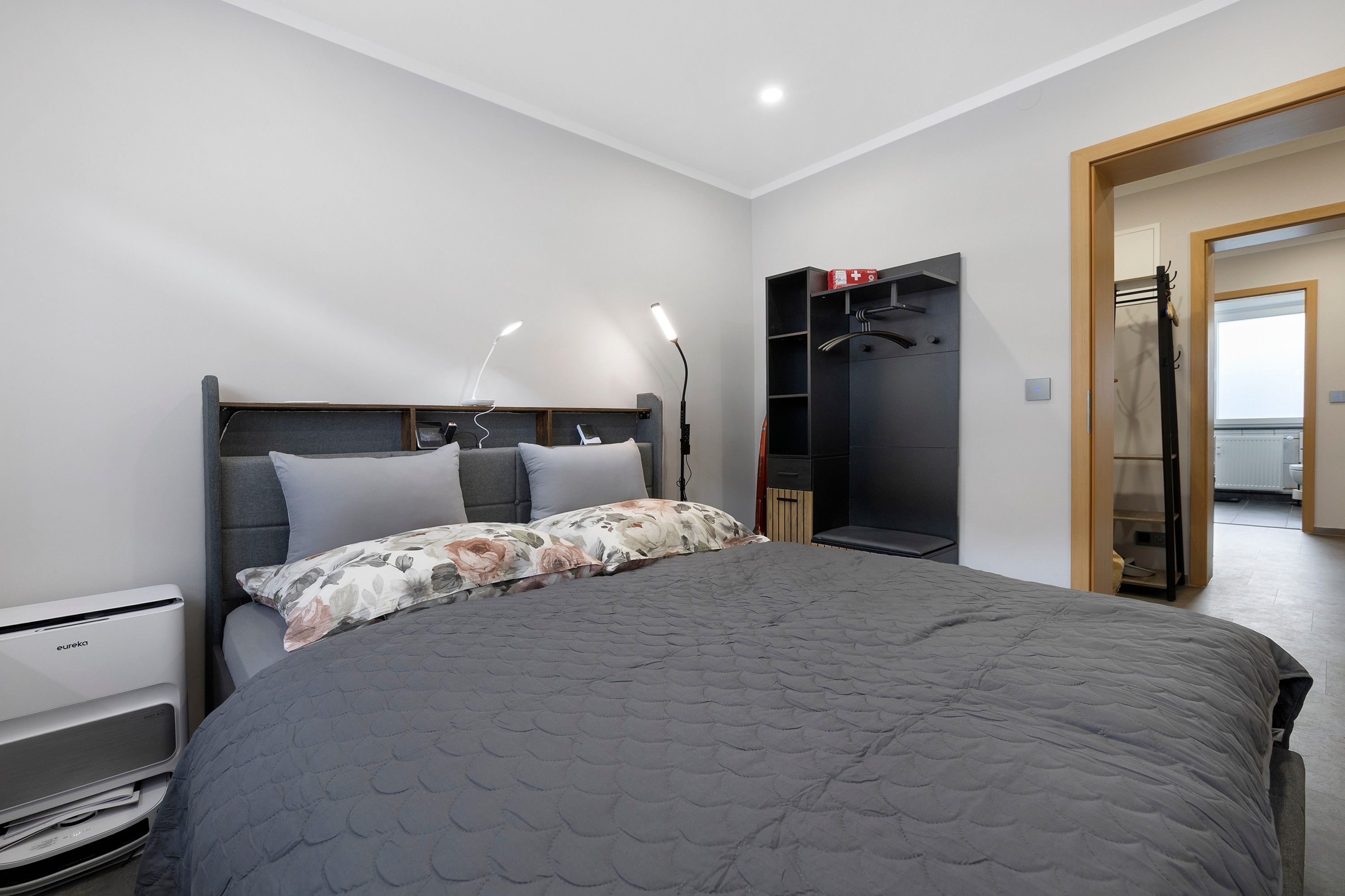 Ein modernes Schlafzimmer mit einem großen Bett, Nachttischlampen, einem Kleiderschrank und einer Heizung.