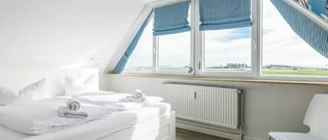Un dormitorio con cama, un radiador, una ventana con cortinas y vistas al paisaje.