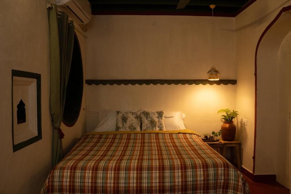 Un dormitorio con una cama, una mesita de noche, una planta en maceta y un cuadro colgado en la pared.