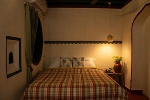 Un dormitorio con una cama, una mesita de noche, una planta en maceta y un cuadro colgado en la pared.