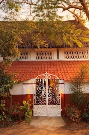 A gated entrance with a decorative metal gate, a red-tiled roof, and a white wall with a window. - Maison Verona Pool Villa Pondicherry (Kottakuppam)