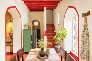 Un comedor con mantel a cuadros, un jarrón con flores y un armario verde.