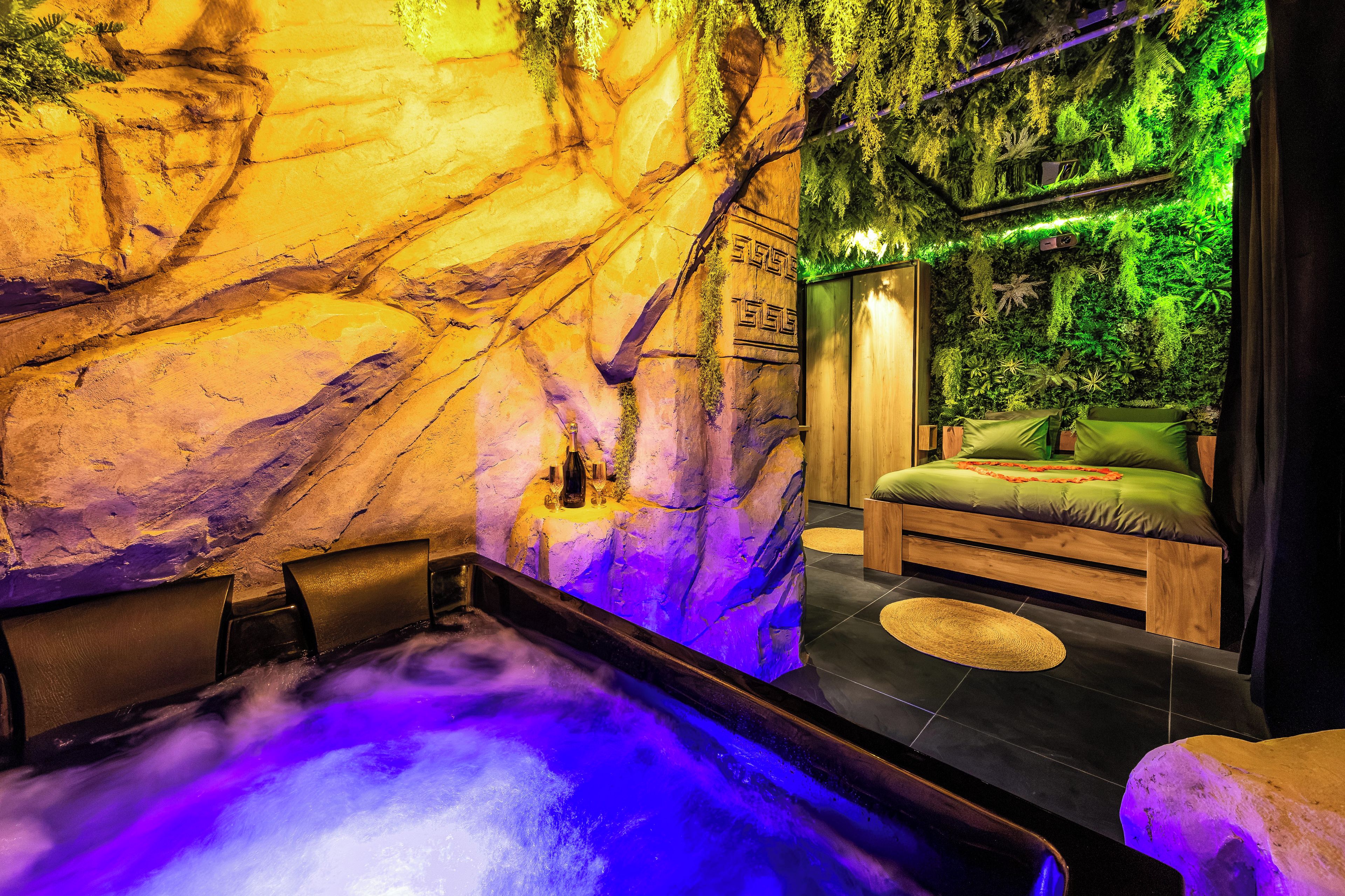 A spa room with a hot tub, a wooden bed, and a wall with a green wall decor.