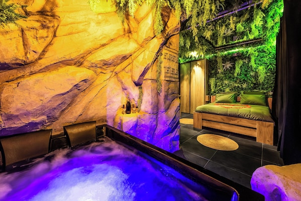 Un cuarto de spa con una bañera de hidromasaje, una cama de madera y una pared decorada con motivos verdes.