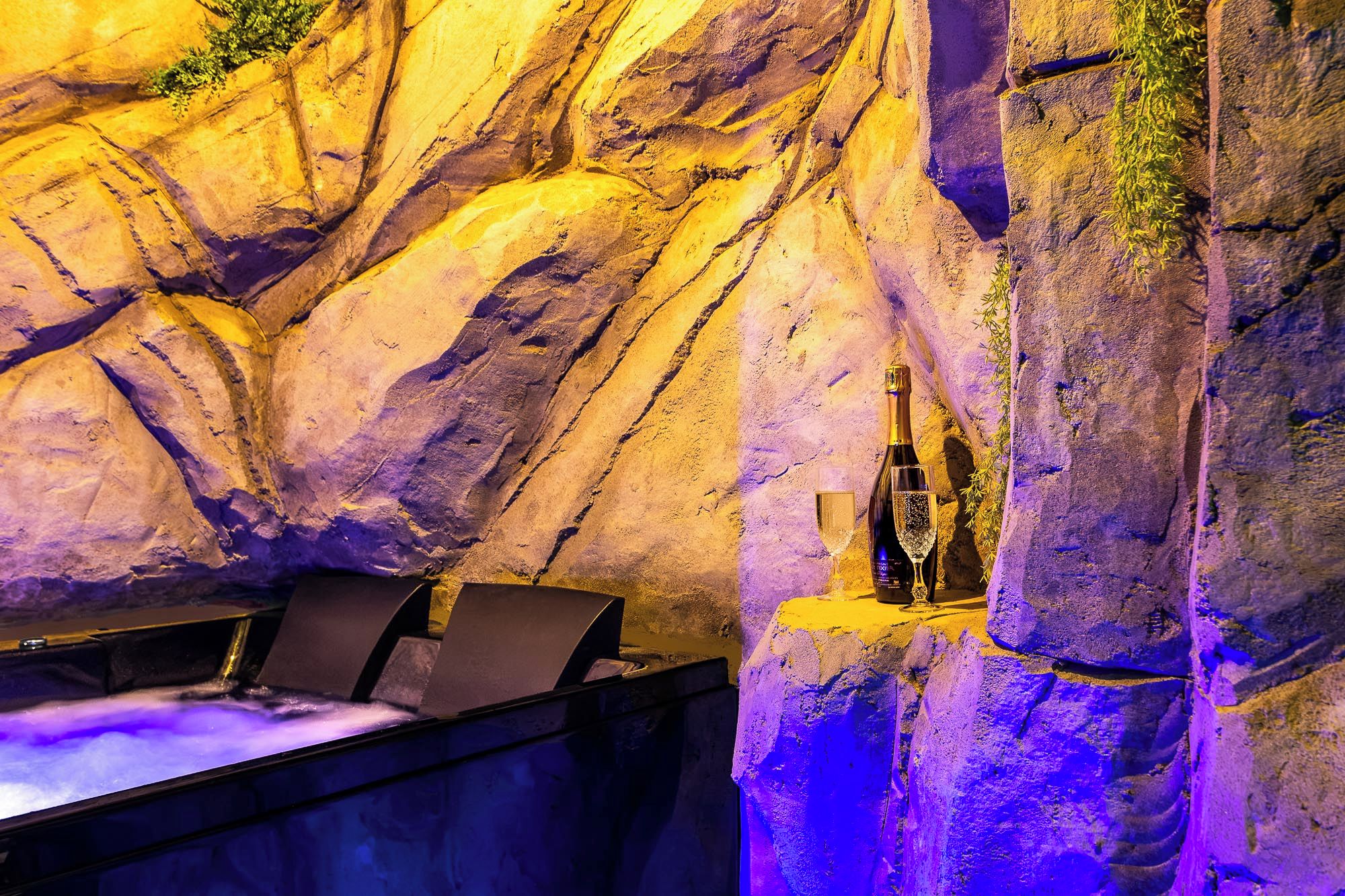 A bar area with a bottle of champagne and a glass on a rock wall.