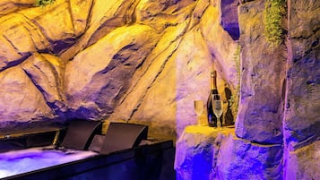 A bar area with a bottle of champagne and a glass on a rock wall.