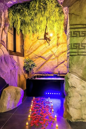Zona de spa con pared de roca, planta colgante y un sendero con velas.
