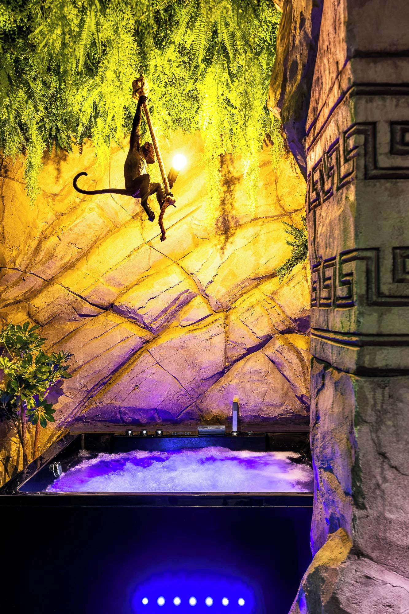 Un singe se produisant sur une corde dans un enclos ressemblant à une grotte, avec une piscine au fond.