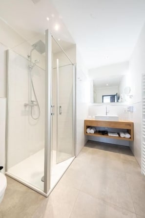 Une salle de bain moderne avec une douche à parois de verre, un meuble-lavabo en bois et un miroir au-dessus du lavabo.
