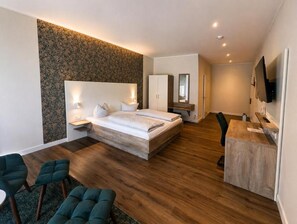 Une chambre d’hôtel moderne équipée d’un grand lit, d’un bureau, d’une chaise et d’un téléviseur.