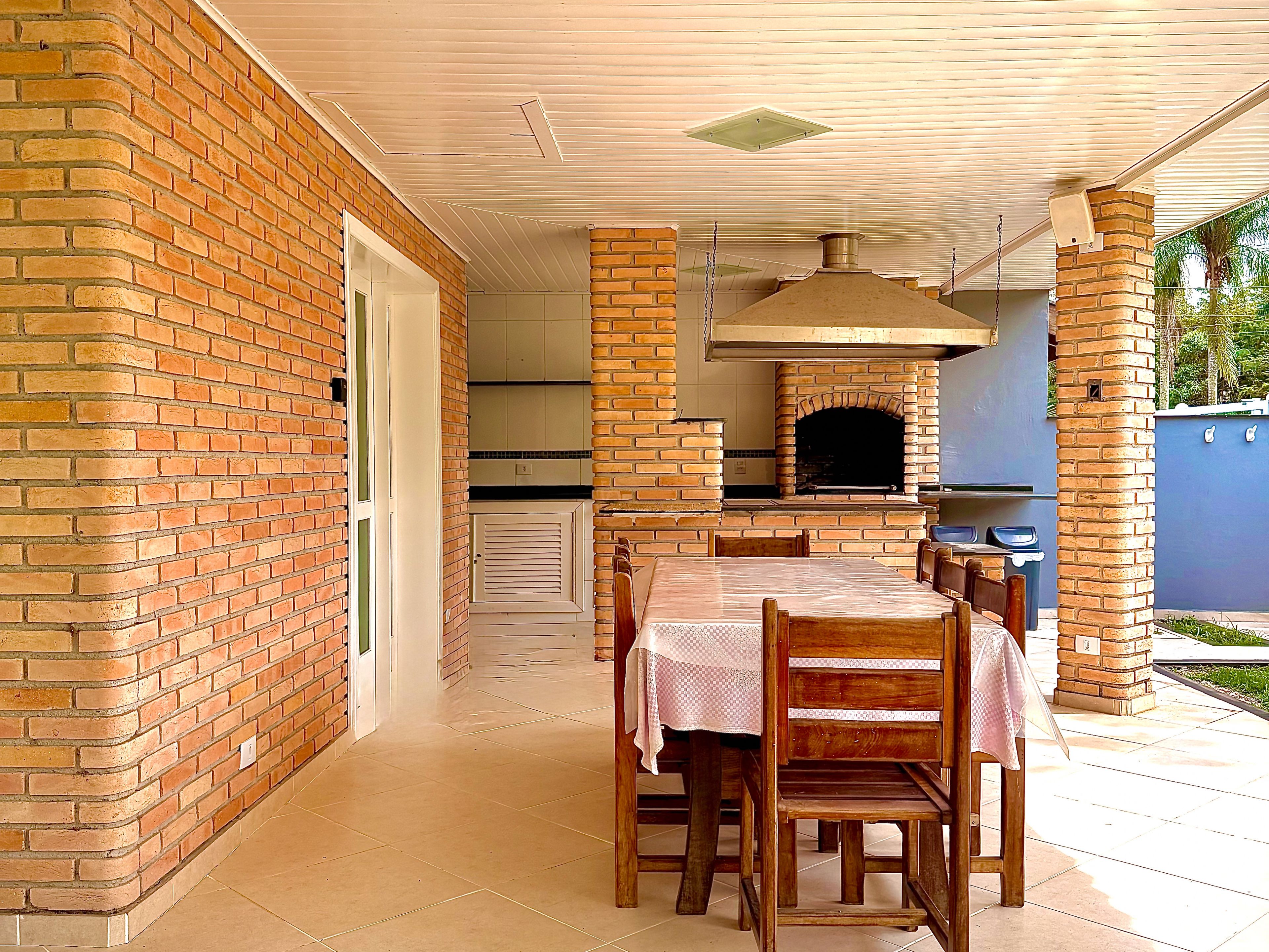 An outdoor patio with a brick wall, a brick oven, and a dining table with chairs.