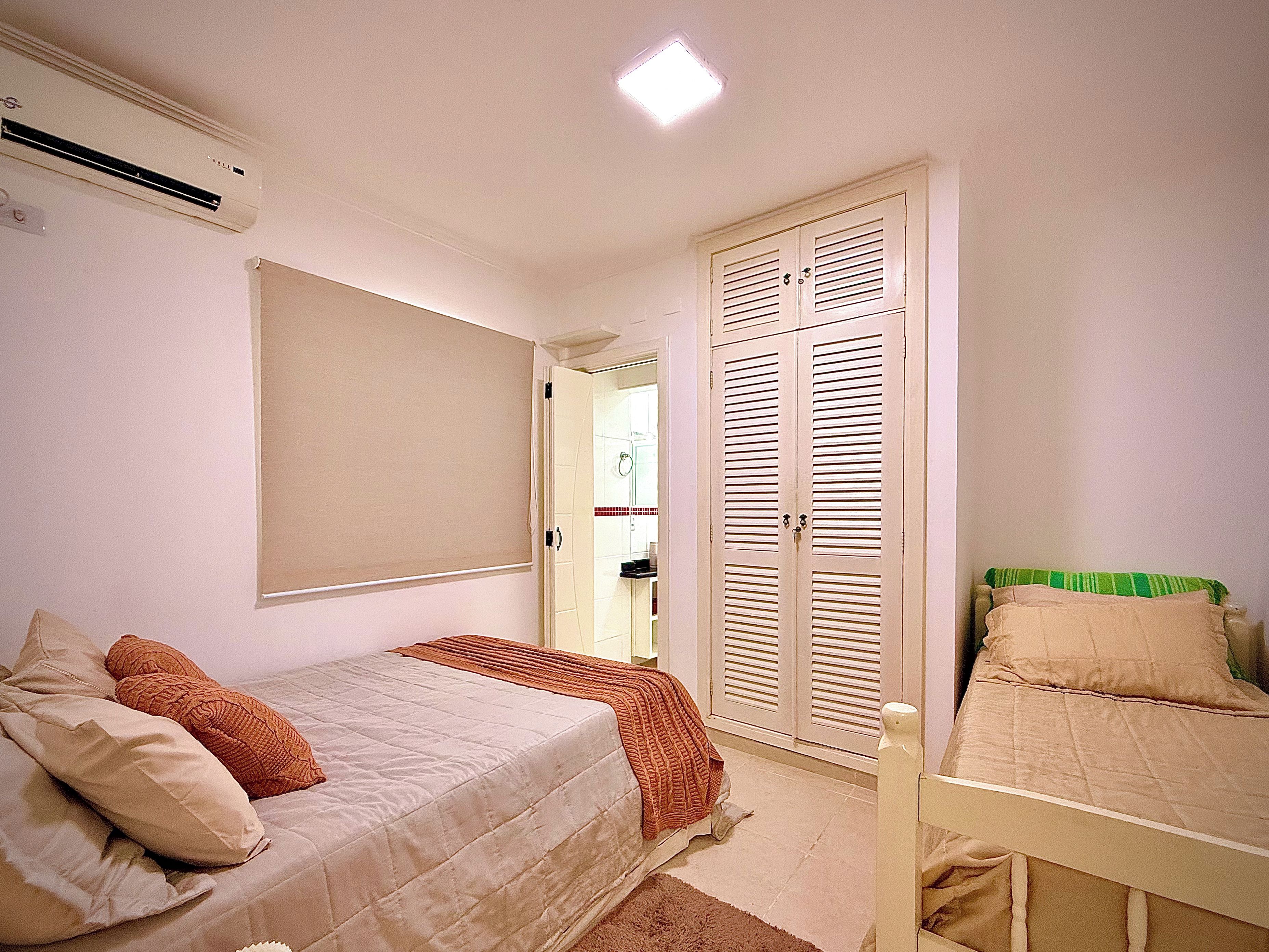 A bedroom with a bed, a wardrobe, and an air conditioning unit.