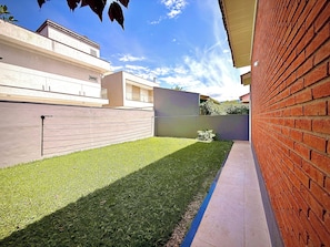 Un espace extérieur moderne doté d’une pelouse bien entretenue, d’un mur en briques et d’une structure à toit plat.