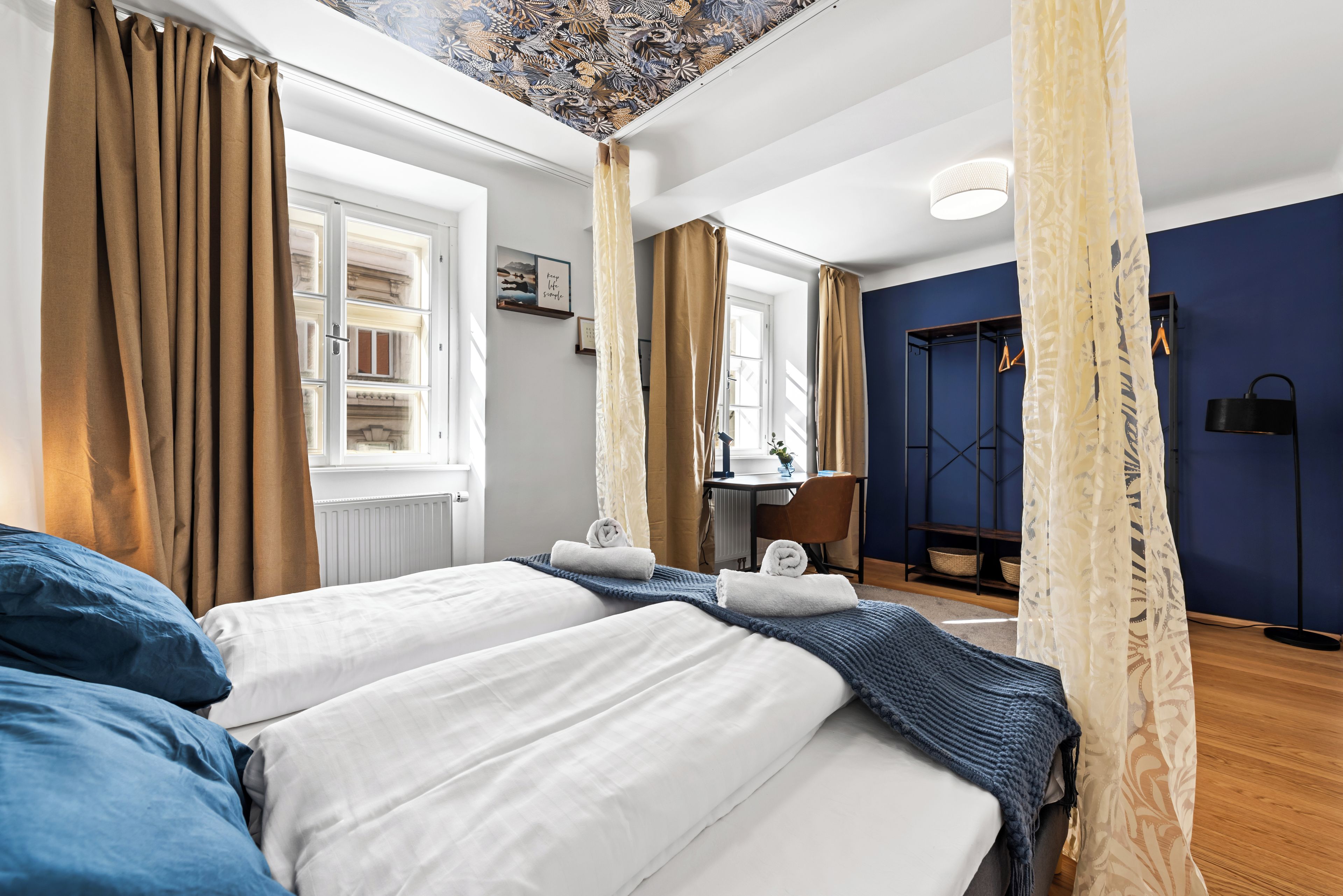 Een hotelkamer met een bed, bureau, stoel, kledingkast en uitzicht op de straat.