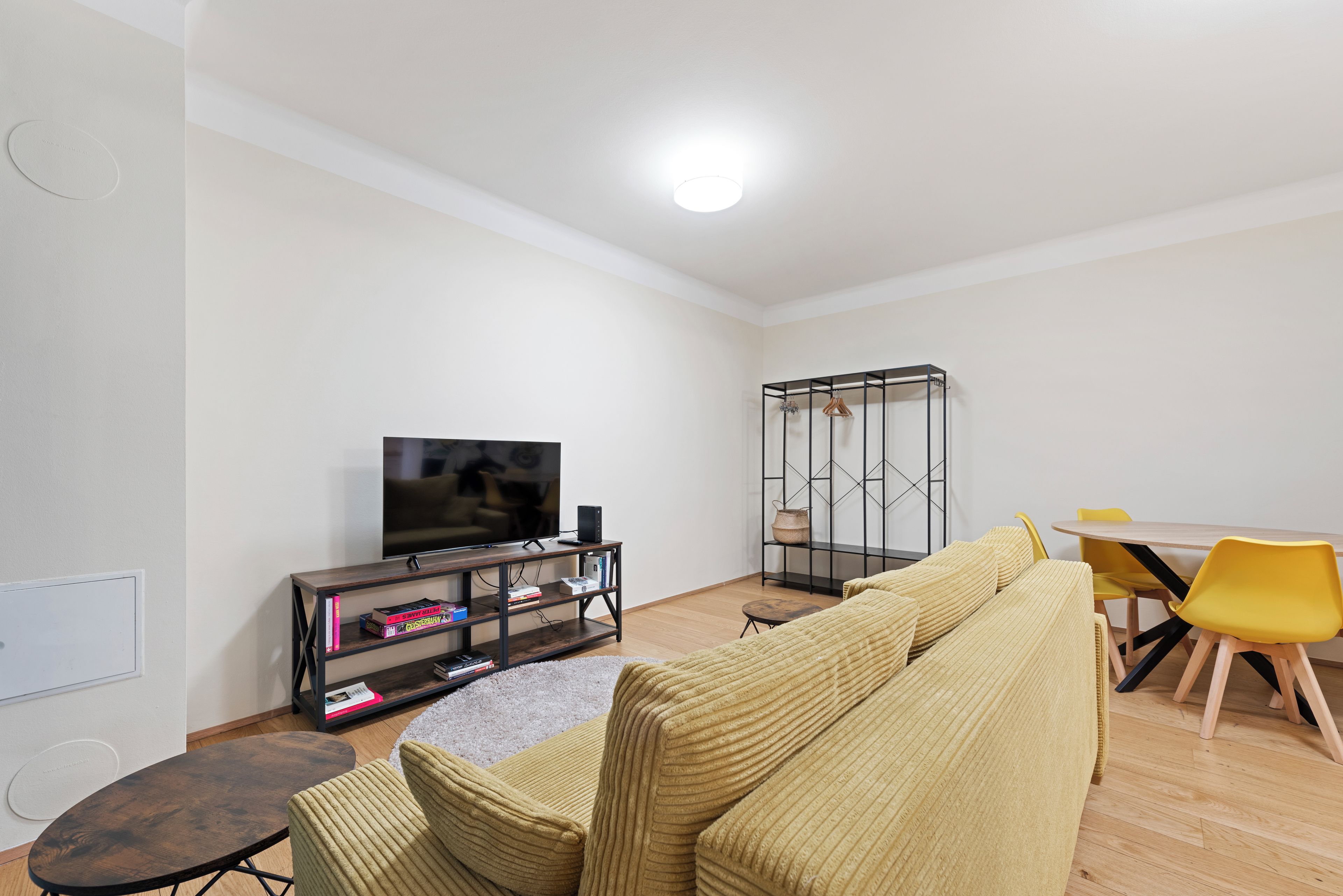 Een moderne woonkamer met een bank, een televisie, een eettafel met stoelen en een boekenkast.