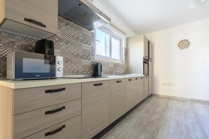 Eine moderne Küche mit Mikrowelle, Kaffeemaschine und einem Fenster über der Arbeitsfläche.