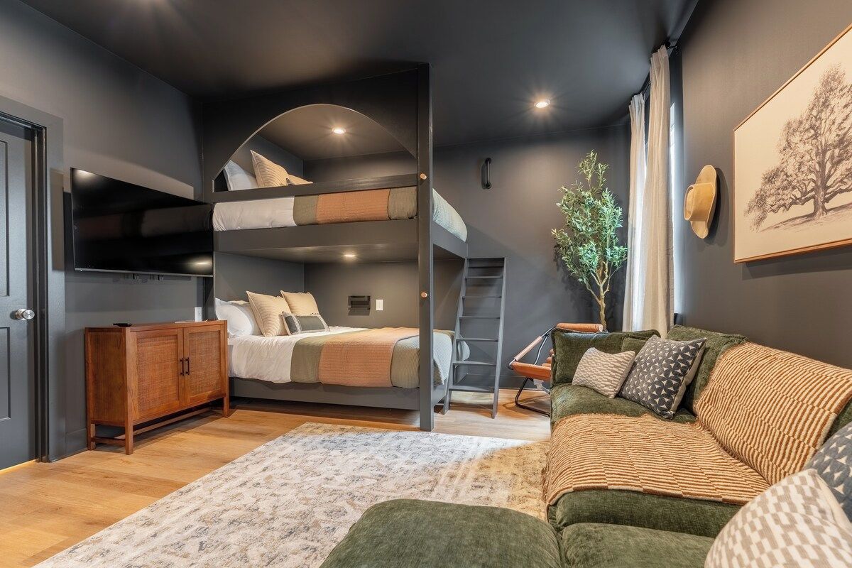 A modern bedroom with bunk beds, a sofa, a cabinet, and a ladder.