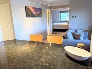 A modern kitchen with a granite countertop, a white bowl, and a dining area with two chairs. - 30 Day+ Quiet, 2 BR/1 BA Condo in Congress Park (Denver)
