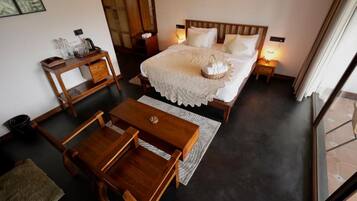 A hotel room with a bed, bedside tables, a wooden coffee table, and a view of the outside.