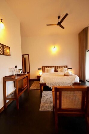 Una habitación de hotel con cama, mesita de noche, lámpara y ventilador de techo.