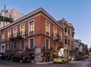 A multi-story building with a red facade, multiple balconies, and a ground-level entrance with a sign. - Art Space Residencies Α1 (Athina)