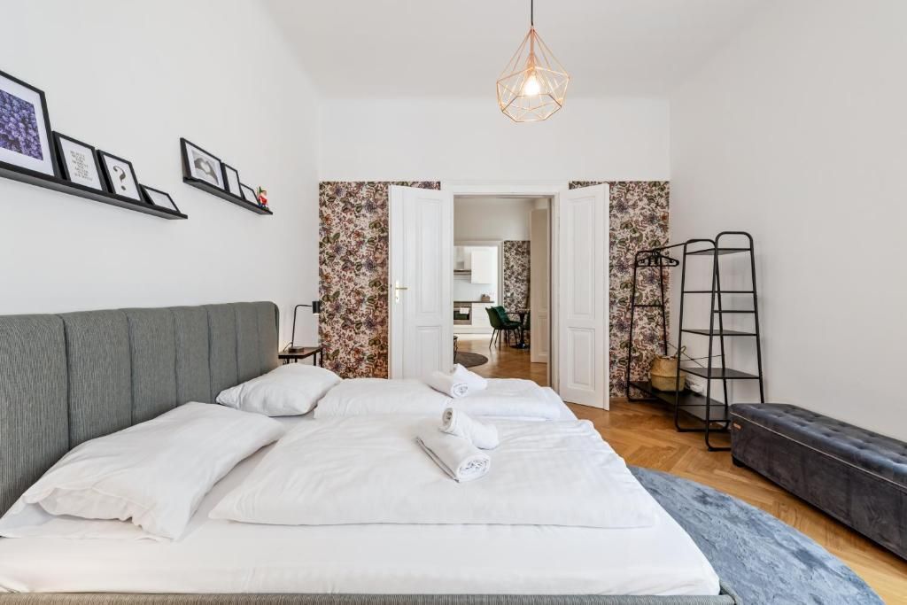 Habitación de hotel con una cama grande, una mesita de noche, una lámpara colgante y vistas a la habitación contigua.
