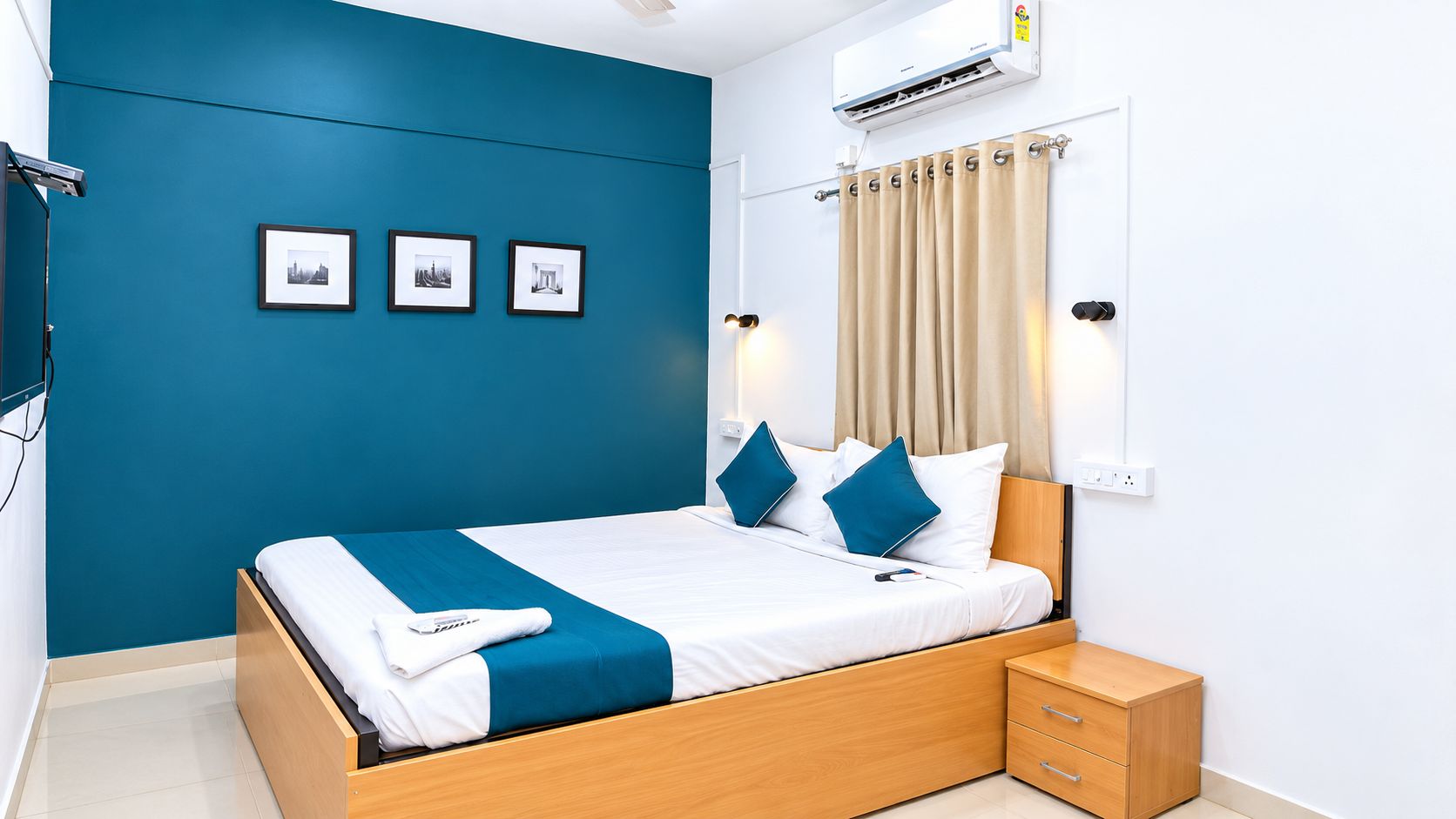 A modern bedroom with a bed, bedside tables, a wall-mounted air conditioner, and framed pictures on the wall.