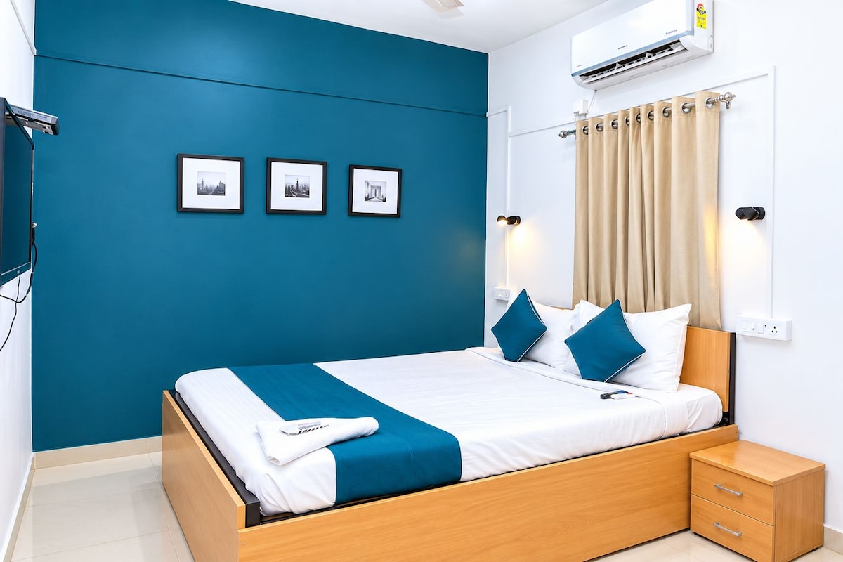 A modern bedroom with a bed, bedside tables, a wall-mounted air conditioner, and framed pictures on the wall.