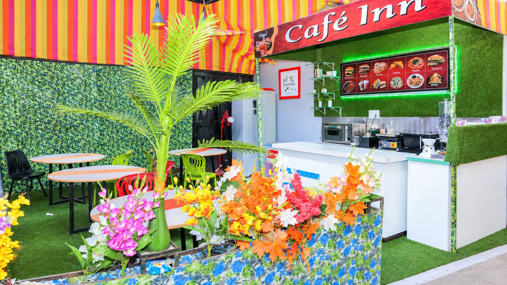 A café with a colorful striped awning, a menu board, and outdoor seating with tables and chairs.
