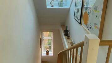 A wooden staircase with a white railing leading to a landing with a skylight.