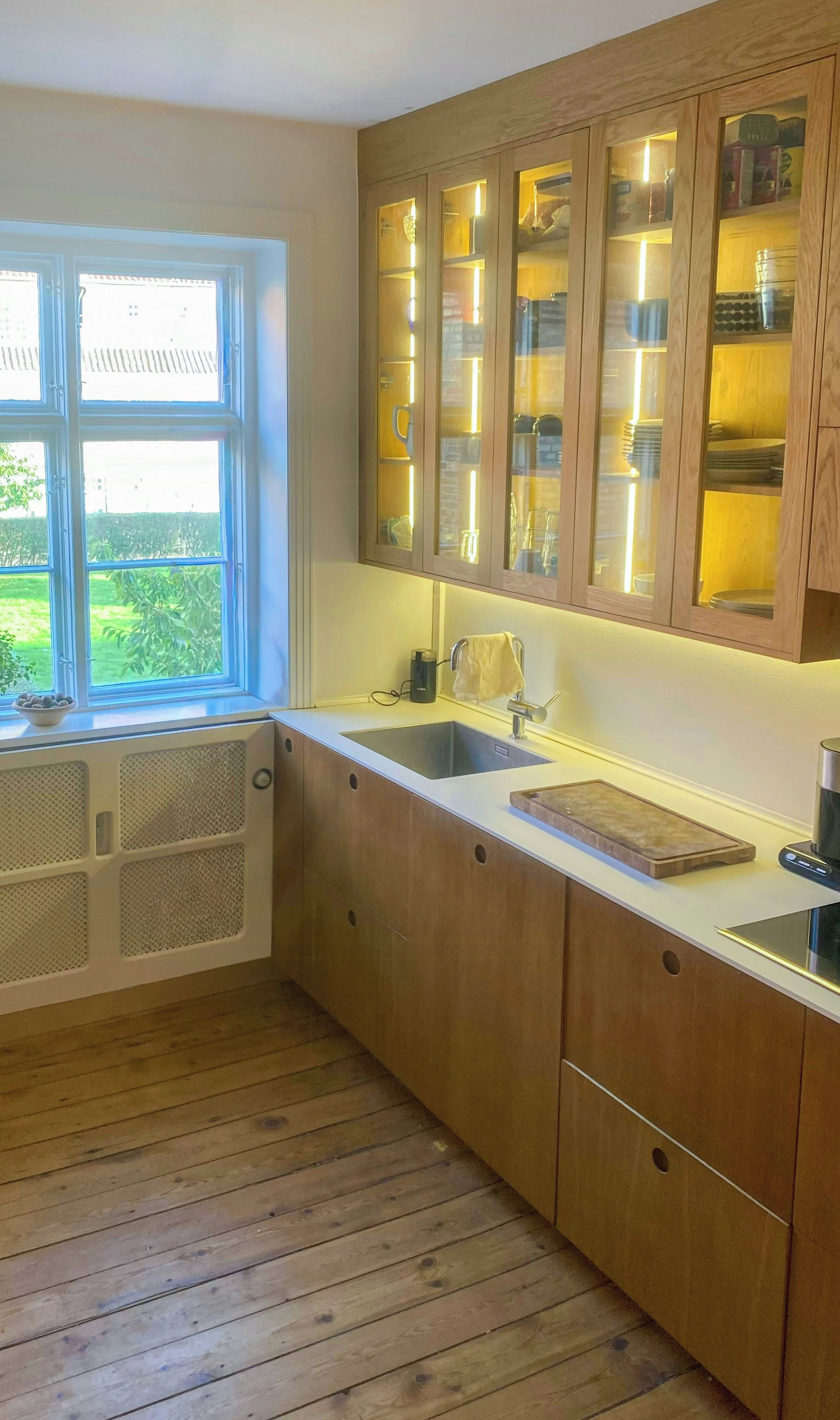 Eine Küche mit Holzschränken, einem Spülbecken und einem Fenster mit Blick auf einen Garten.