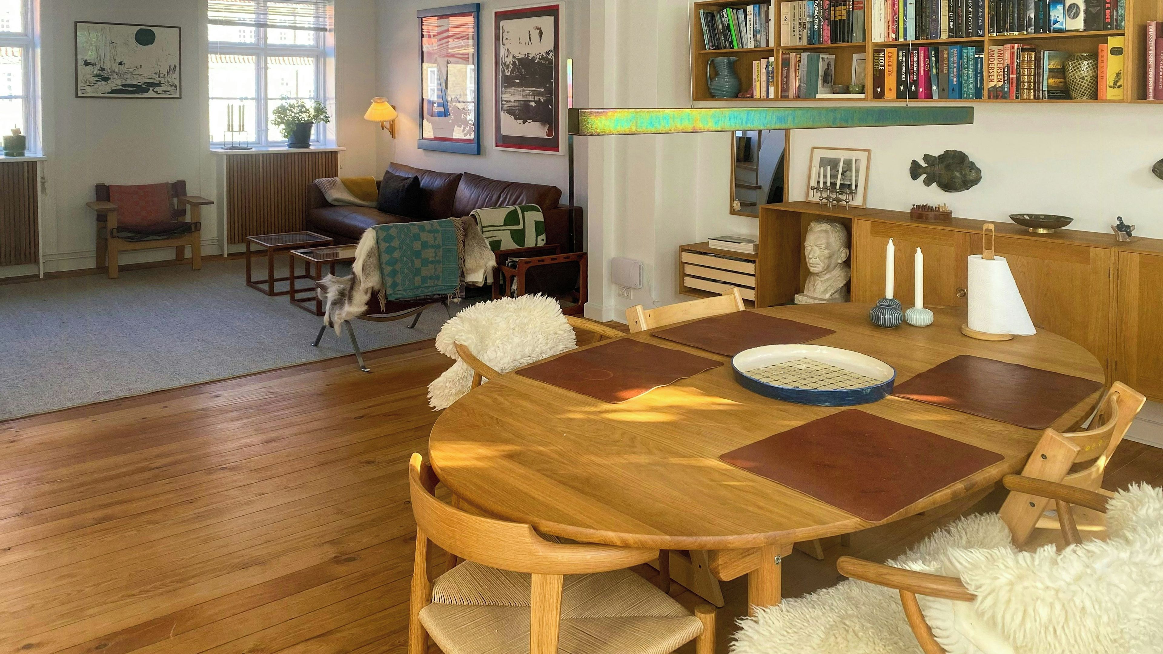 A dining area with a wooden table, chairs, and a bookshelf filled with books.