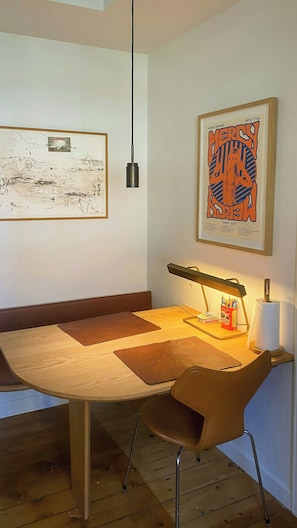 Ein Essbereich mit einem Holztisch, einer modernen Lampe und Kunstwerken an den Wänden.