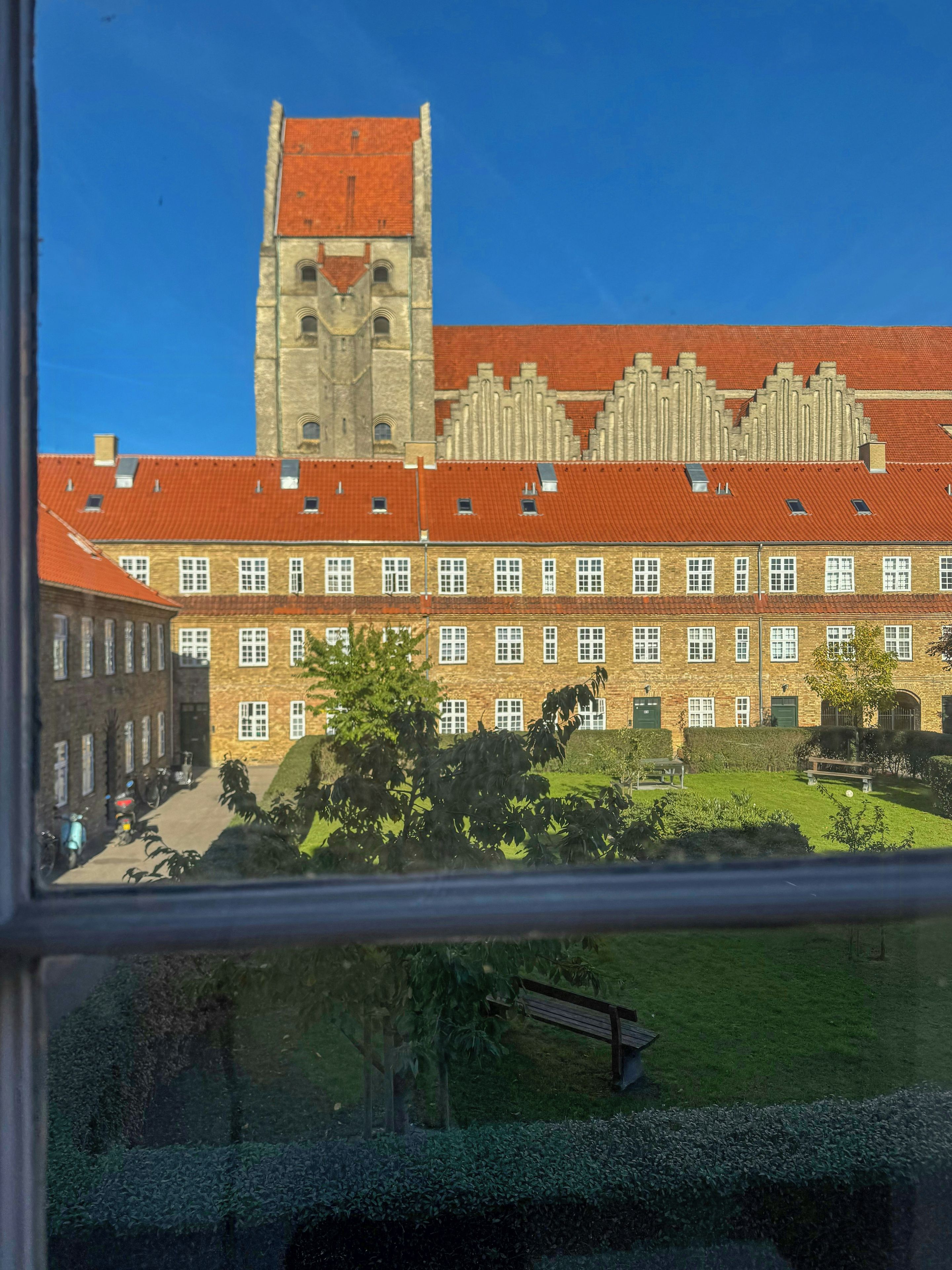 A building with a prominent tower and a courtyard with a bench.