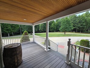 A covered porch with a wooden ceiling, white railings, and a view of a well-maintained lawn and trees. - Private & Peaceful 5-bedroom Retreat (Newport)