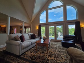 A spacious living room with a large window, a sofa, a coffee table, and a patterned rug. - Private & Peaceful 5-bedroom Retreat (Newport)