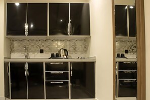 A modern kitchen with black cabinets, a white countertop, and a patterned backsplash. - SOLEVA Serviced Apartments (Jeddah)