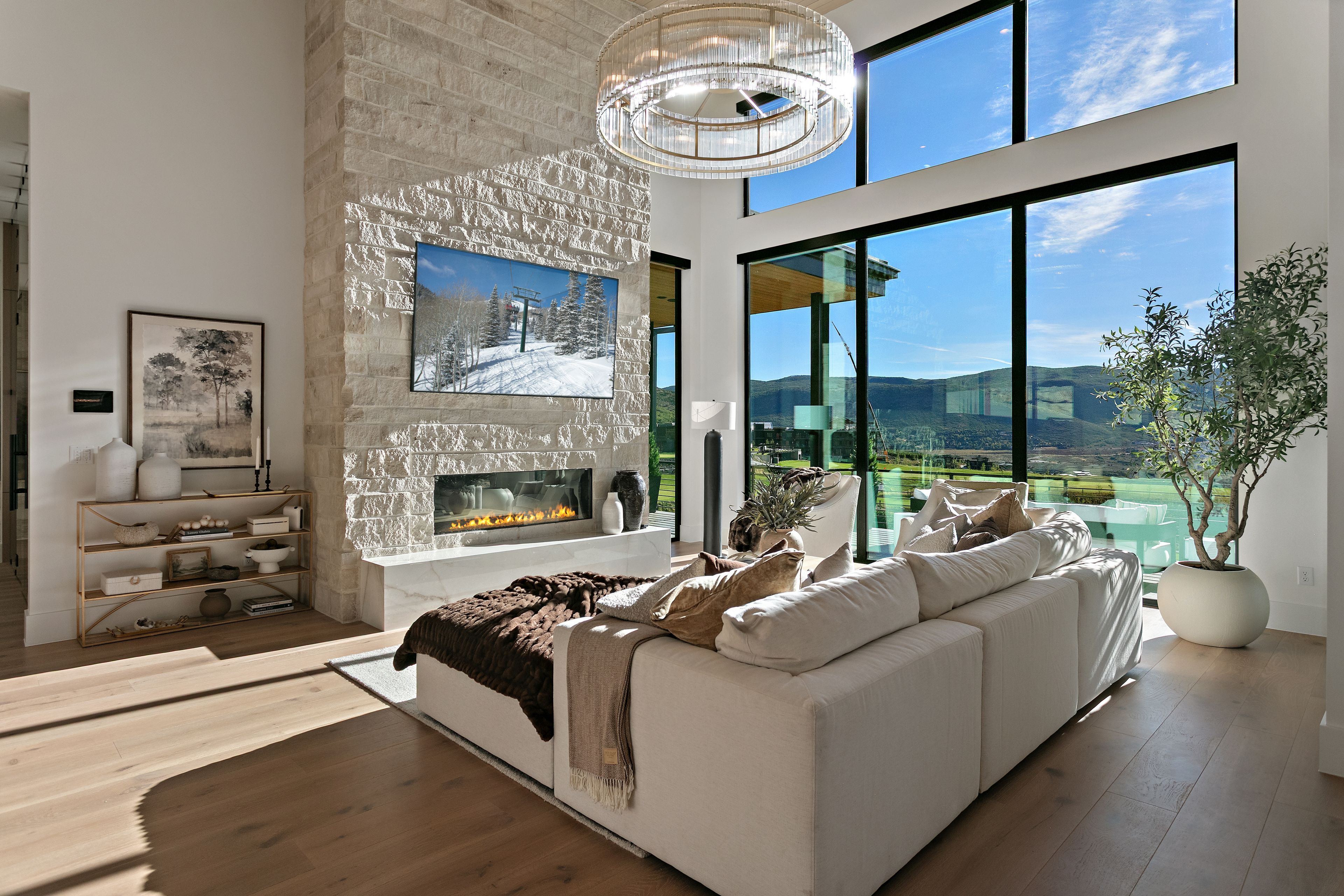 A modern living room with a fireplace, a large sofa, and a view of the outdoors.