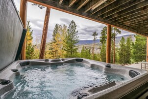 Ein Whirlpool mit Blick auf eine gebirgige Landschaft durch Holzrahmenfenster.