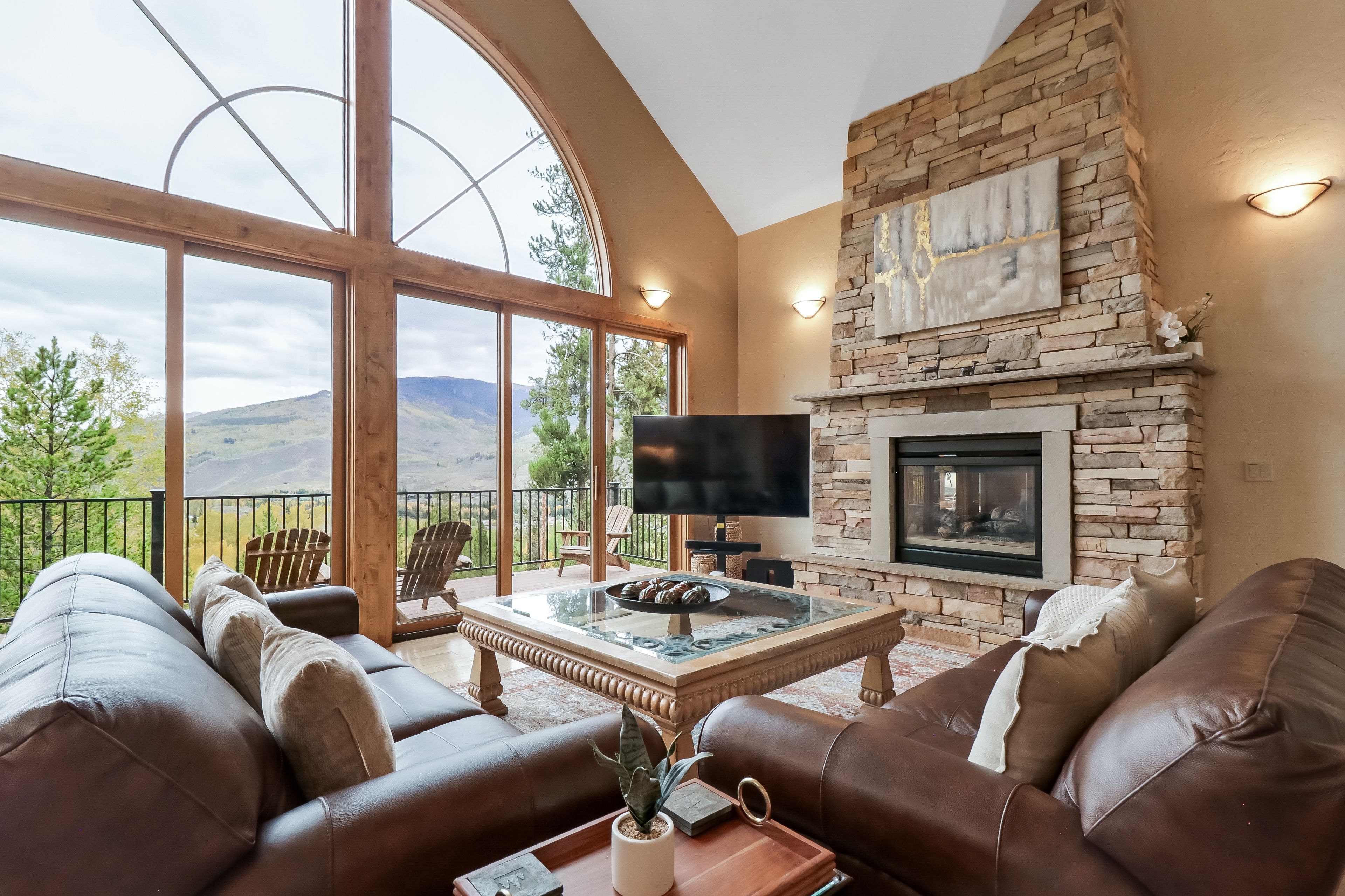 A living room with a stone fireplace, leather sofas, a coffee table, and a TV.