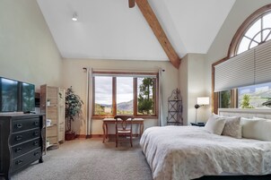 Ein Schlafzimmer mit Bett, Schreibtisch, Stuhl, Fernseher und einem Fenster mit Blick ins Freie.